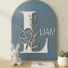 Navneskilt i træ med navnet Liam, blomsterbogstav i støvet blå nuance til indretning af drengeværelse eller dåbsgave.