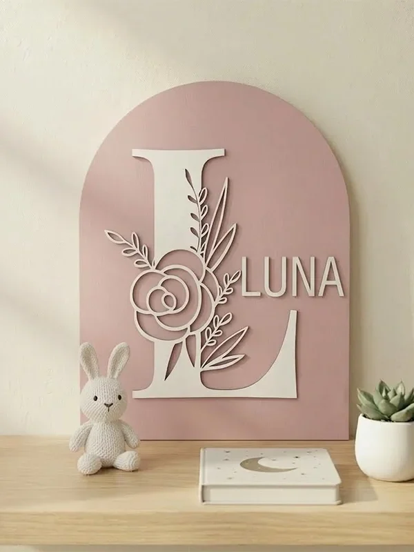 Personligt navneskilt i træ til børneværelse med navnet Luna, gammelrosa blomsterbogstav på hylde med bamse.